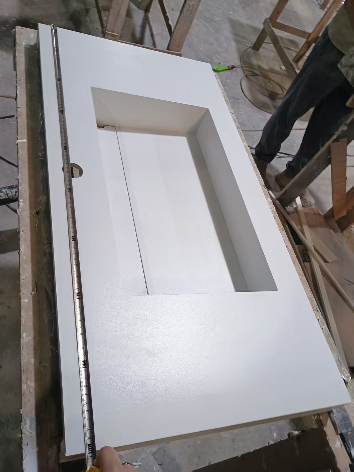 A worker checking a sintered stone basin top with a tape measure before packing at the Vora Surfaces factory